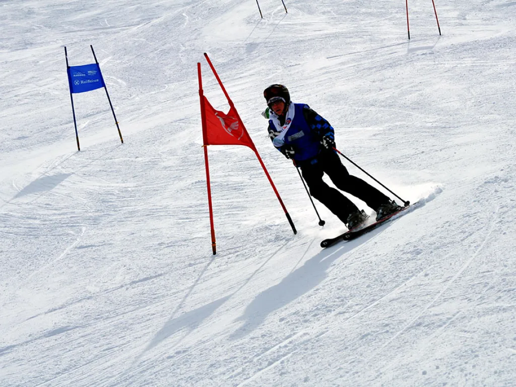 Skifahrer in tiefer Hocke am roten Tor.